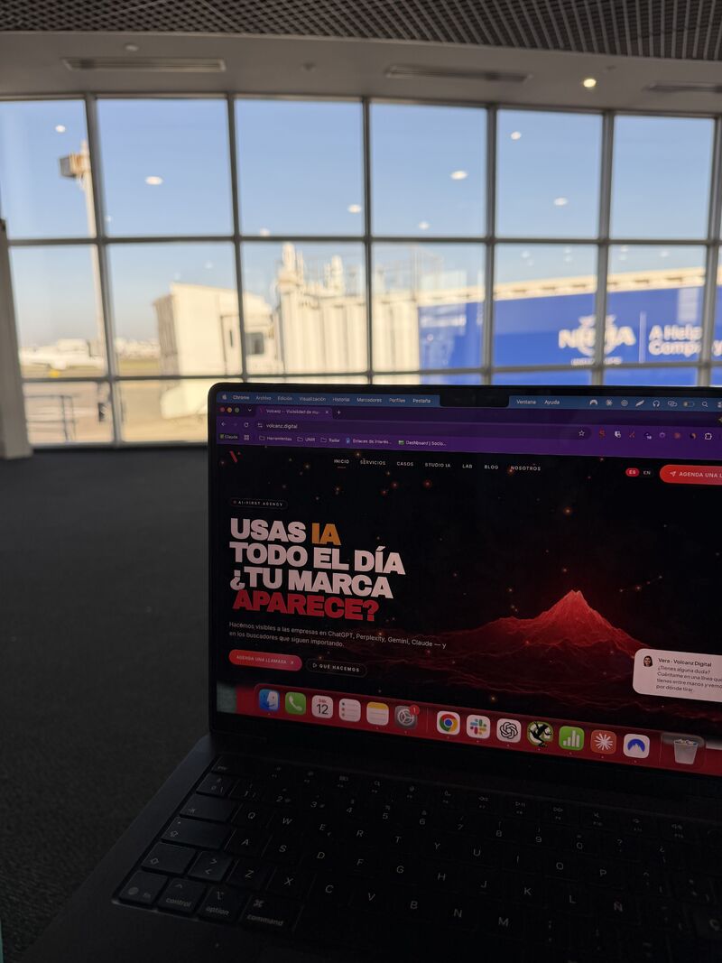 Portátil abierto en una puerta de embarque de un aeropuerto, con la pista y los aviones al fondo a través de la cristalera